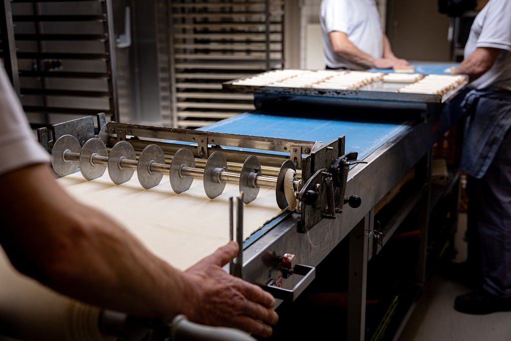 Deeg wordt uitgerold en op maat gesneden in de bakkerij van Van Hassel