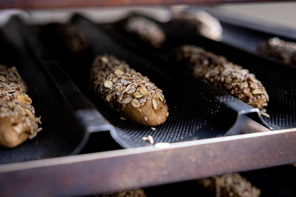 Waldkorn baguettes in de bakvormen, bestrooid met zaden, klaar voor de oven