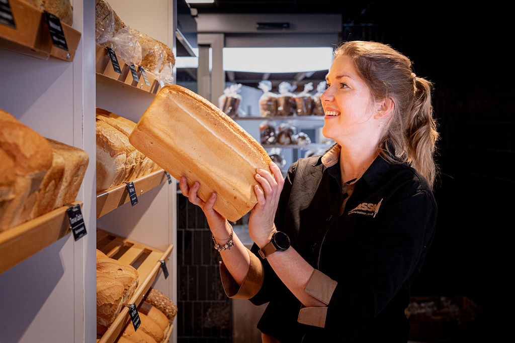 Sabine zet vers brood in de schappen bij de opening van de winkel