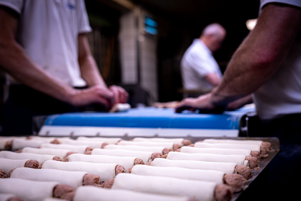 Bakkers pakken met de hand verse worstjes in bij Bakkerij van Hassel in Wernhout